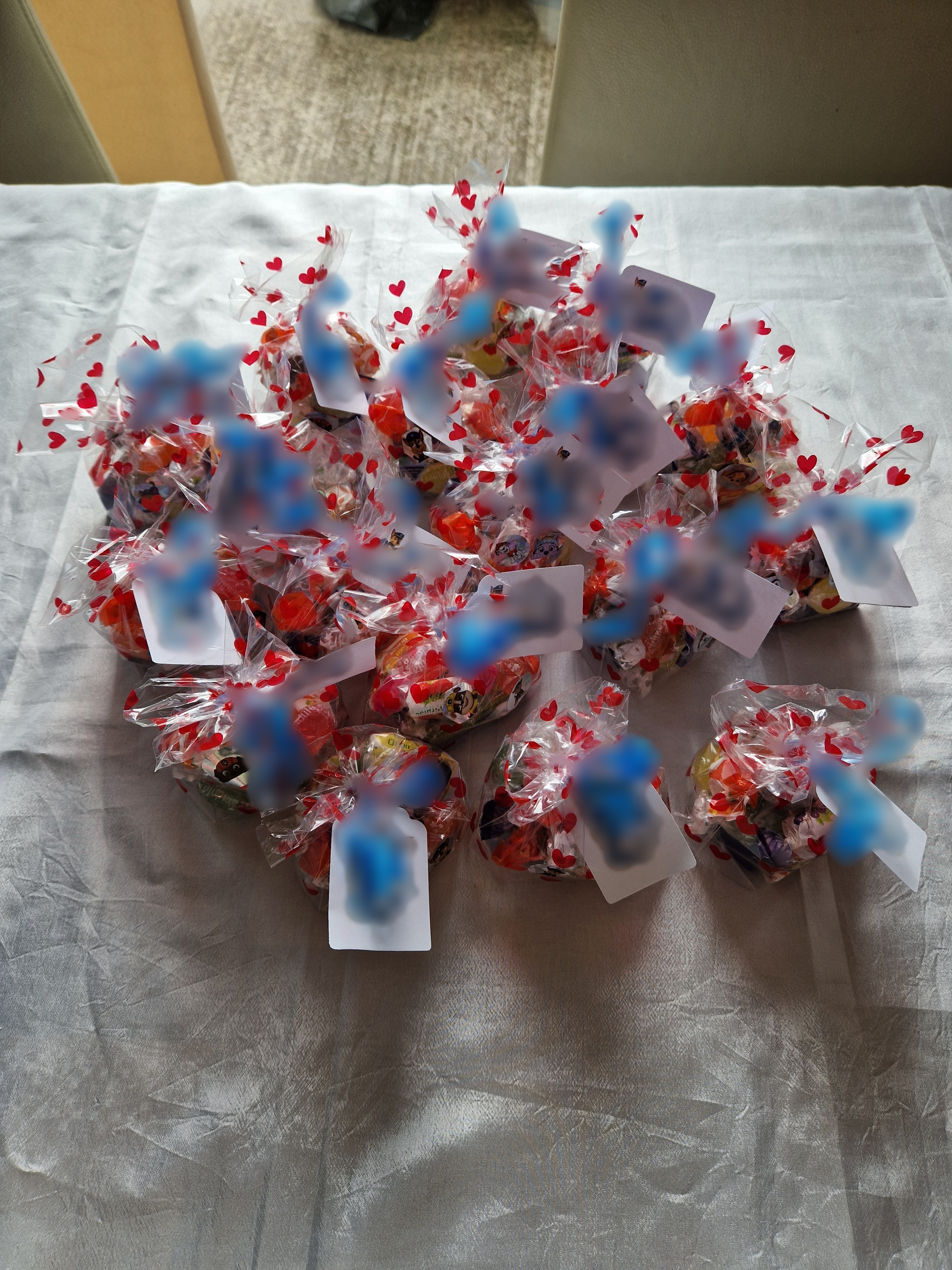 Matériel pour fabriquer les sachets de bonbons : bobine de ruban bleu, perforatrice à étiquettes, ciseaux et cellophane à coeurs