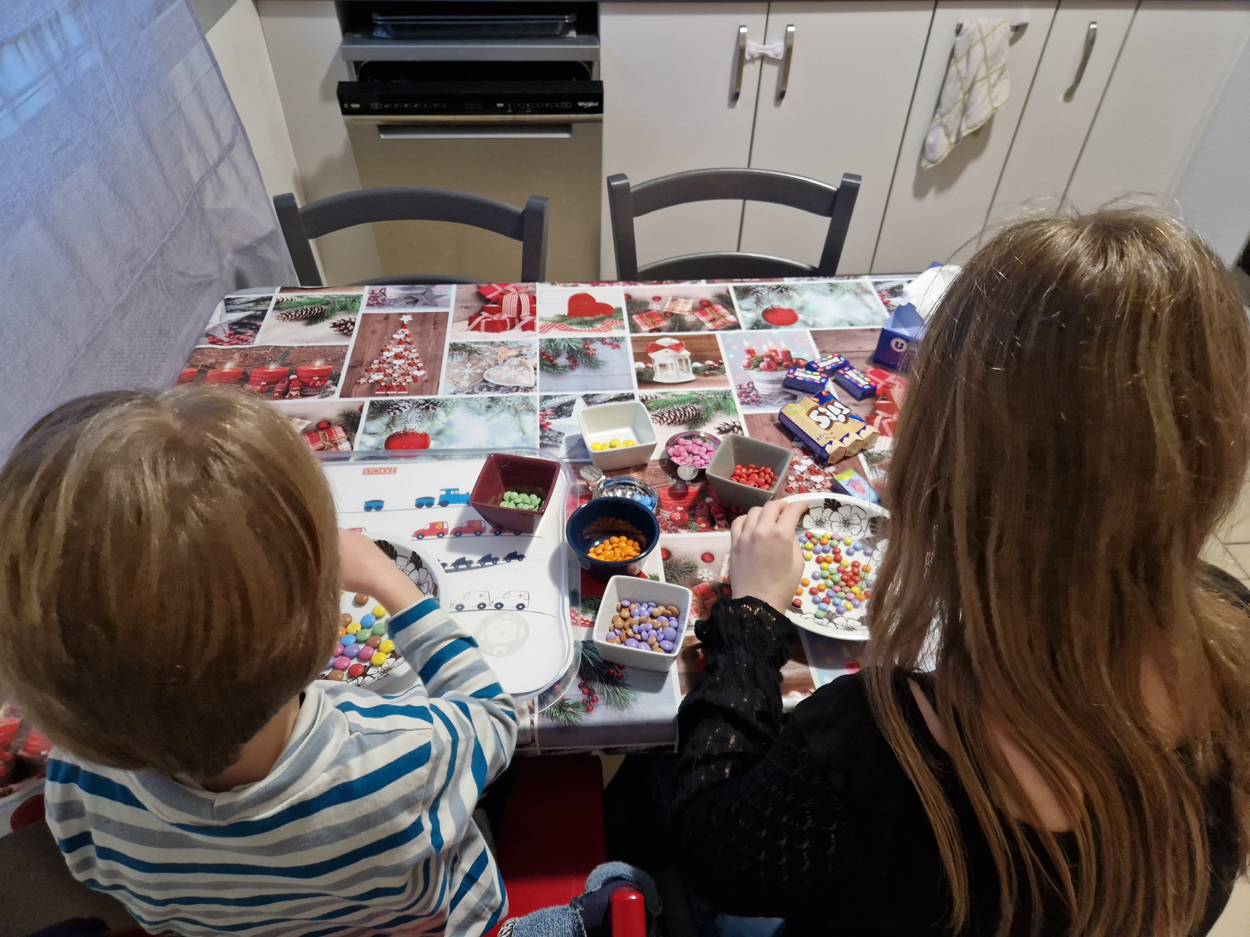 Deux enfants qui trient les smarties par couleur, vus de dos