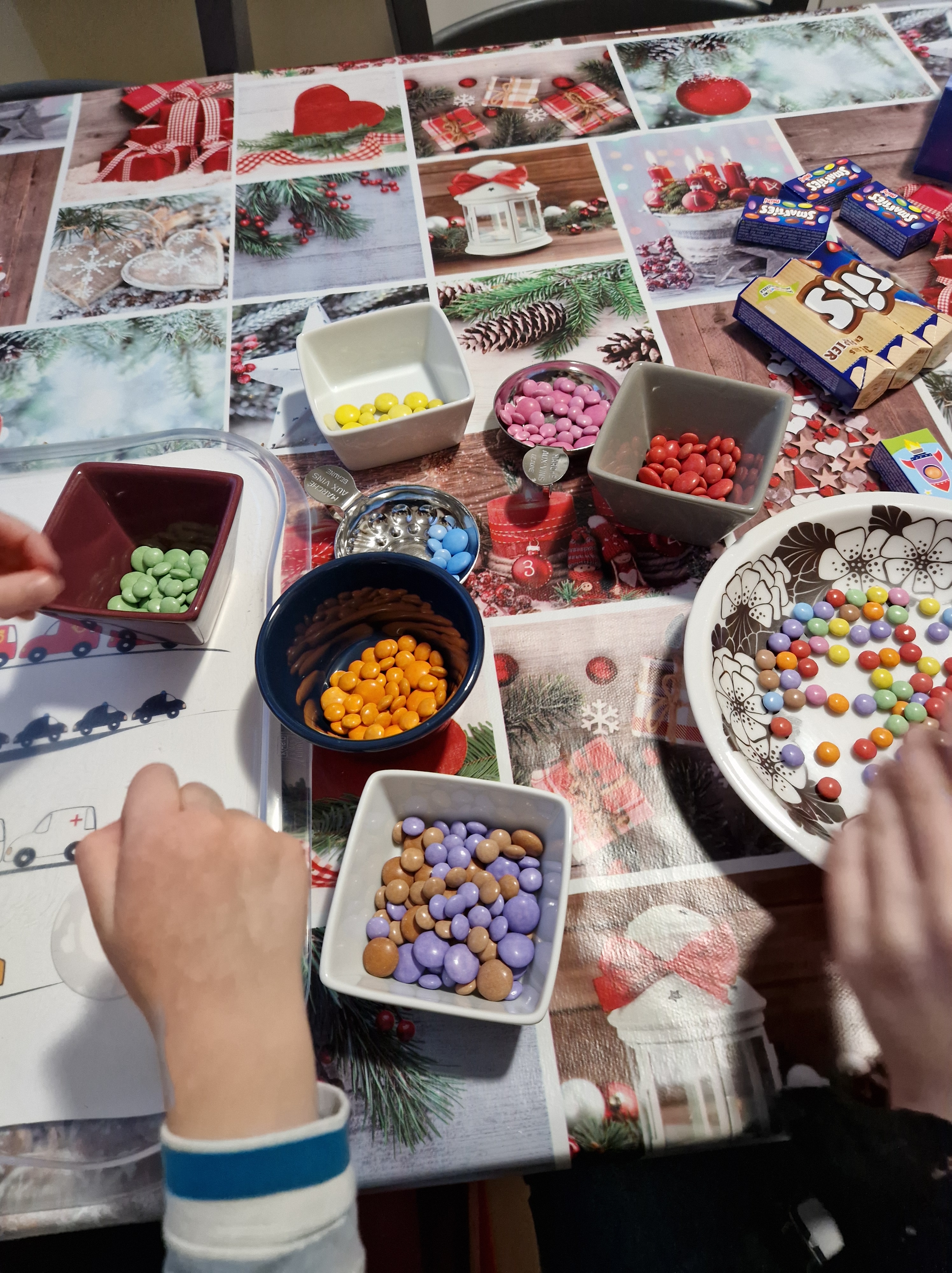 Smarties triés par couleur dans des petites coupelles, prêts pour décorer le gâteau