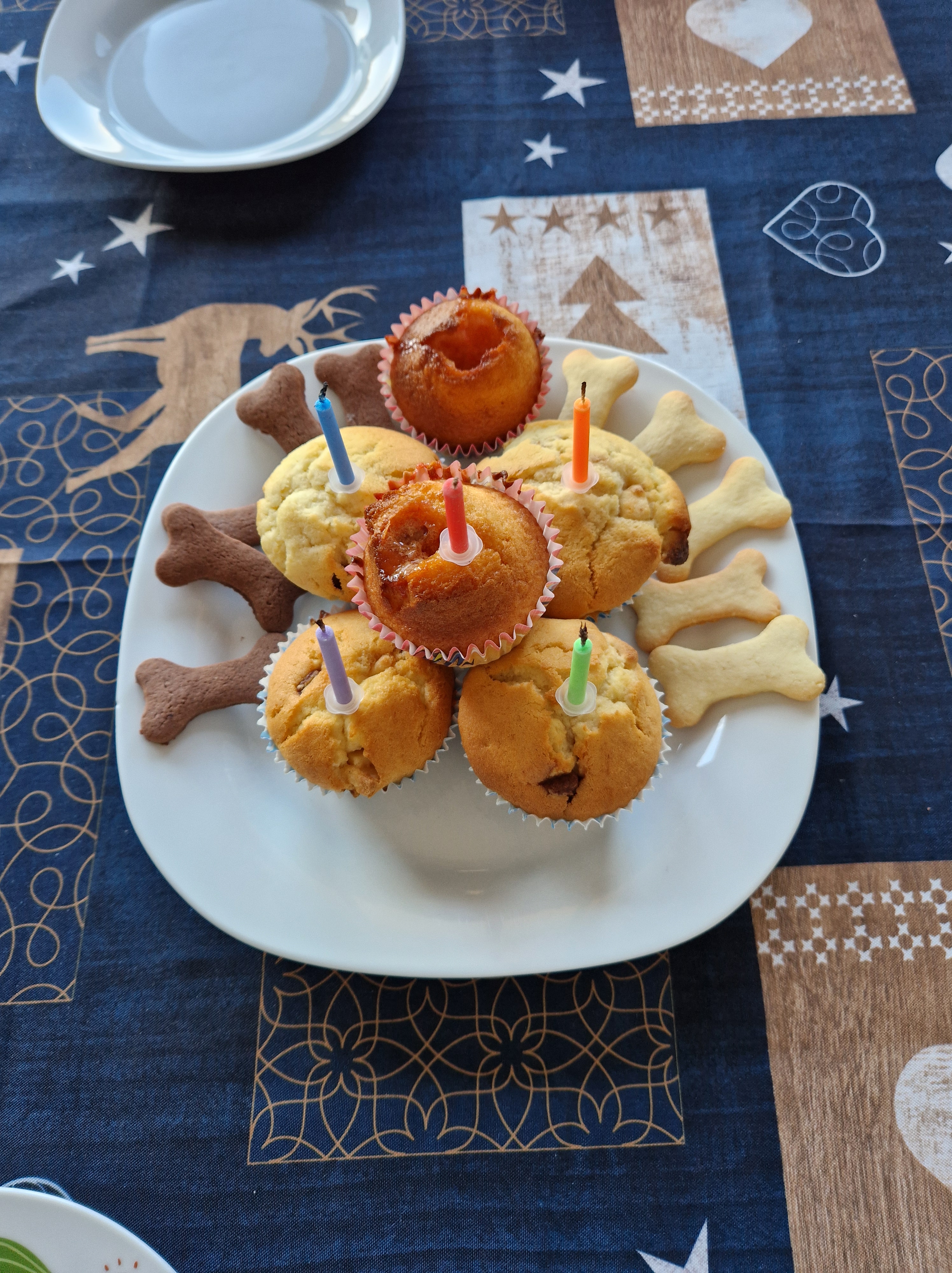 Assiette de muffins avec cinq bougies et sablés en forme d'os, pour le petit-déjeuner d'anniversaire