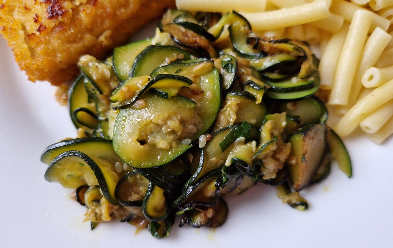 Rondelles de courgettes dorées à la poêle, servies avec des pâtes